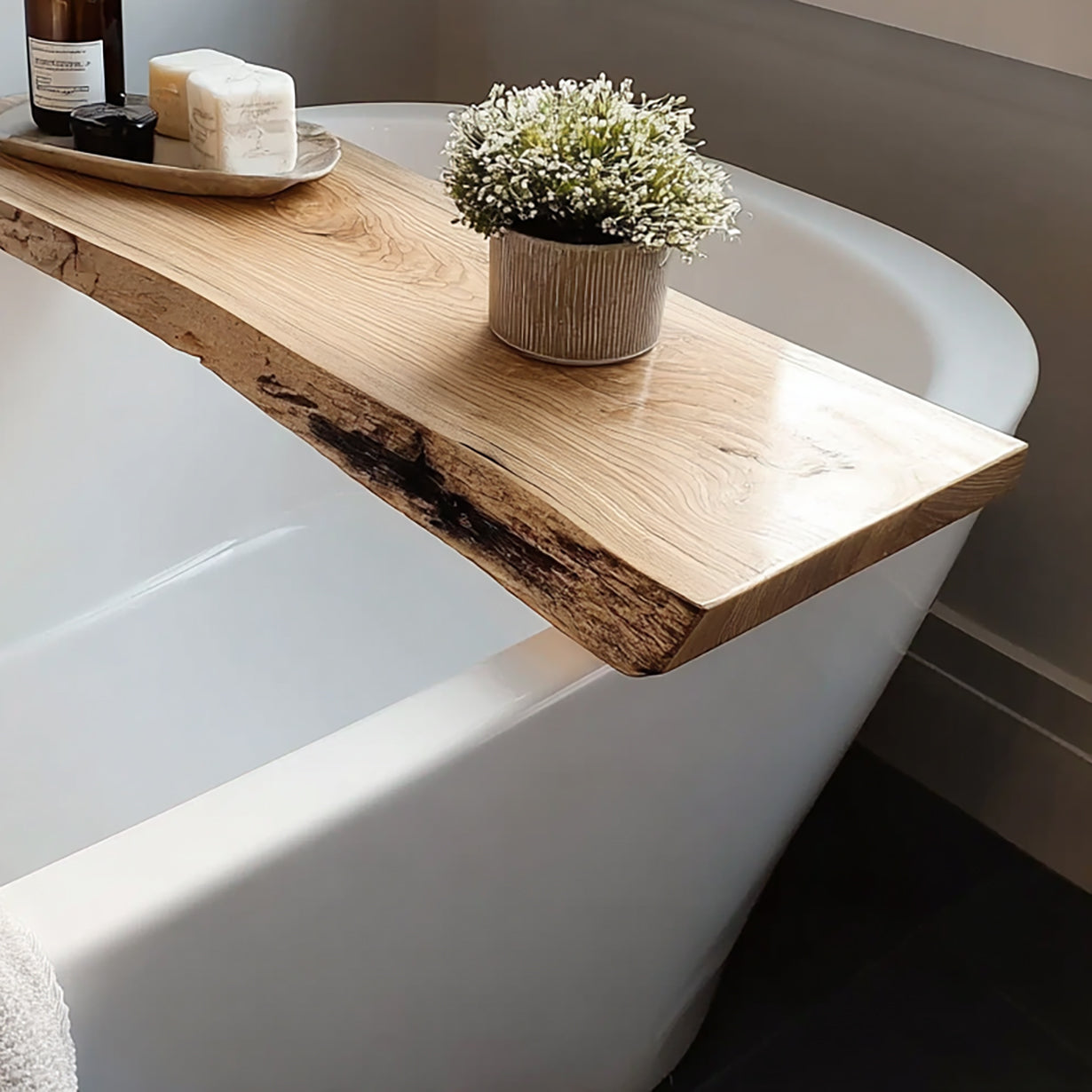 White freestanding bathtub with rustic wooden bath tray holding soap, candle, and potted plant