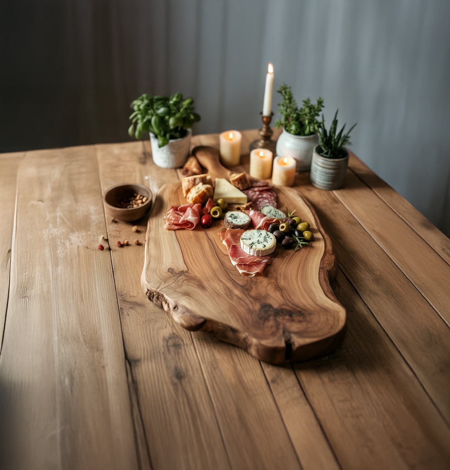 Charcuterie board with assorted cheeses, cured meats, olives, and bread on rustic wooden table with candles and potted herbs