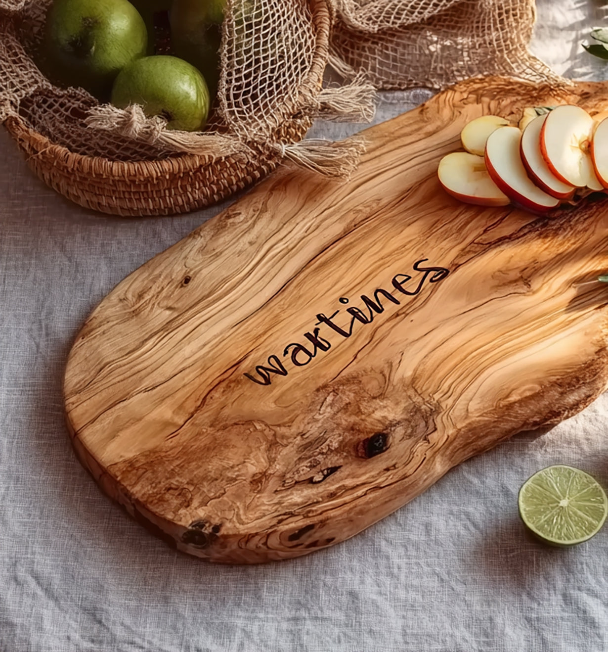 Rustic wooden cutting board engraved with 'wartimes', sliced apples on board, limes in wicker basket