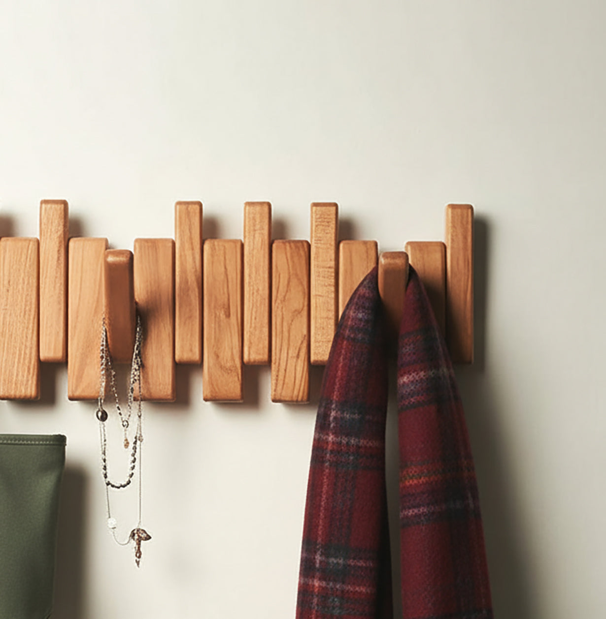 wooden wall-mounted coat rack with hanging jewelry and red plaid scarf